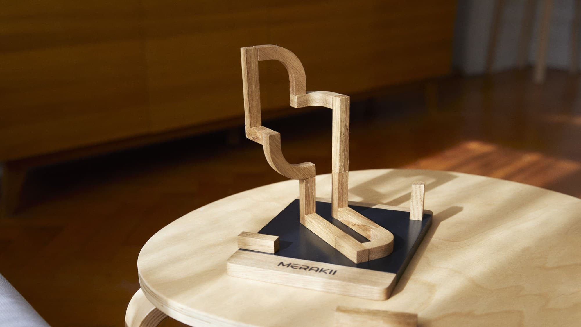 A MERAKII structure on its dark base plate, on a side table in a warm interior